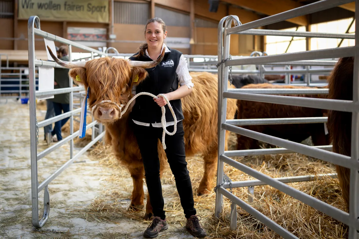 Man sieht eine junge Frau mit einem Hochlandrind.